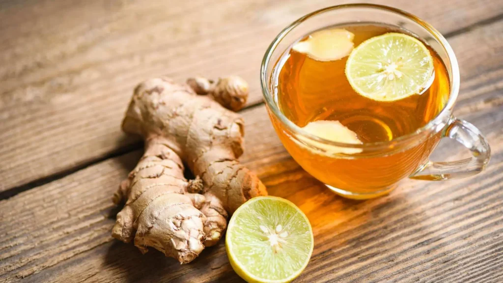 Xícara de chá de gengibre com fatias de limão e pedaços de gengibre fresco ao lado, poderoso anti-inflamatório