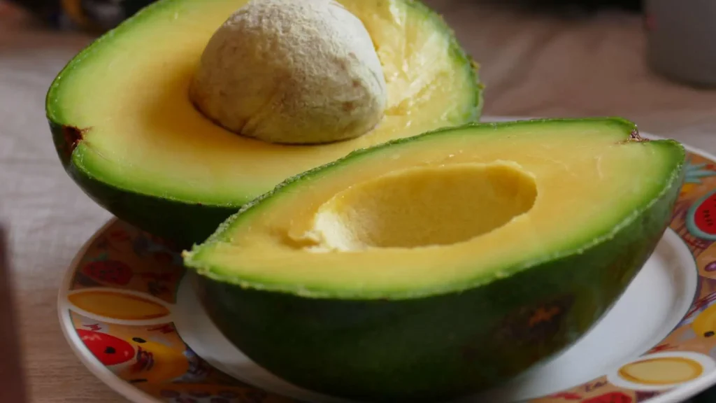 Abacate maduro fatiado ao meio sobre um prato brando decorado